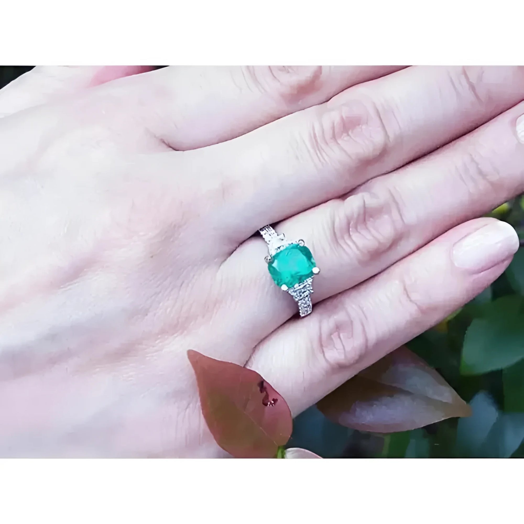 Anillo de compromiso de oro blanco con esmeralda colombiana y diamantes trapezoidales en mano.