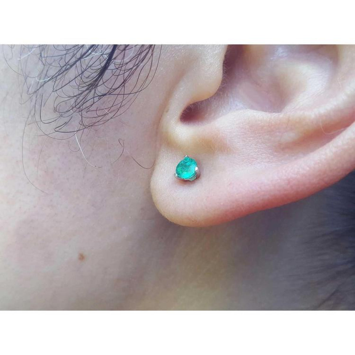 Martini emerald stud earring with a round cut medium deep green emerald in 14K white gold on an ear.