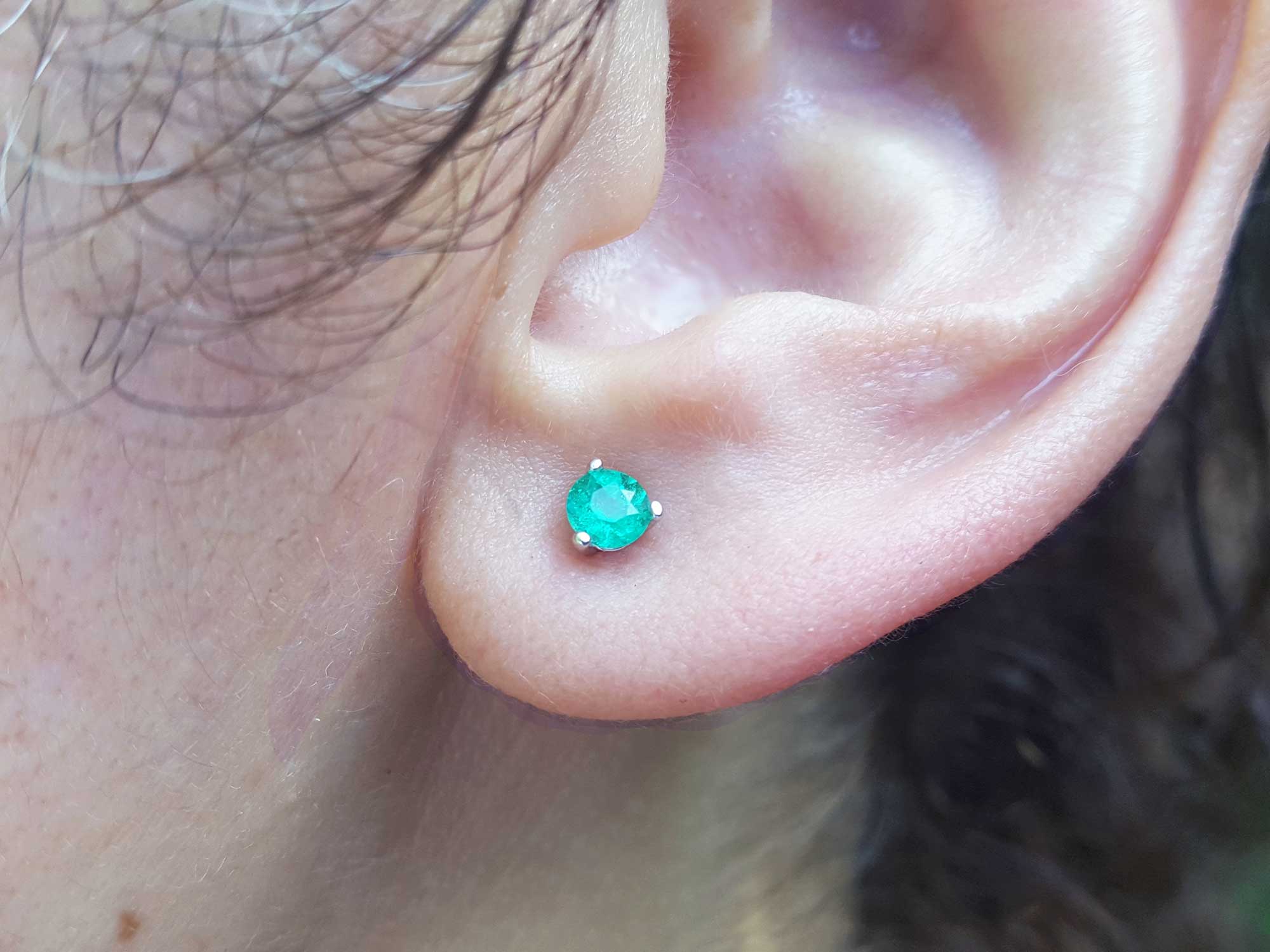 An earlobe wearing a martini emerald stud earring