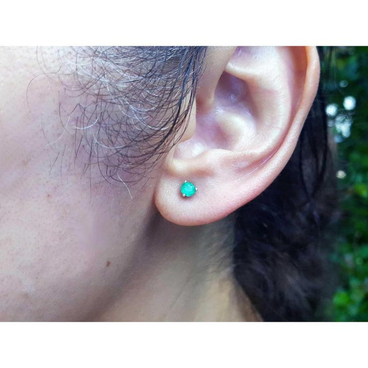 Martini emerald stud earring with a round green emerald in 14K white gold on an ear.
