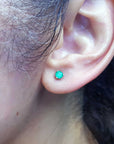 Real emerald stud earrings martini style on a woman's ear.
