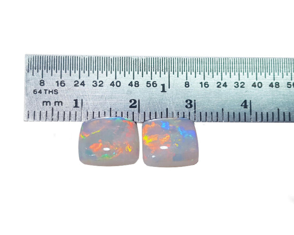 A matching pair of australian opals face up in front of a ruler for size measure.