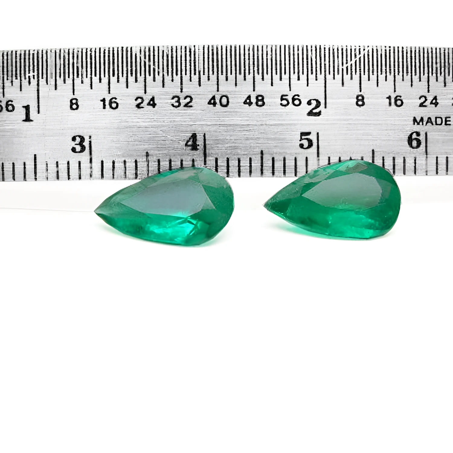 Matched pair of 3.62 carat pear-cut bluish-green Colombian emeralds with a ruler for scale.