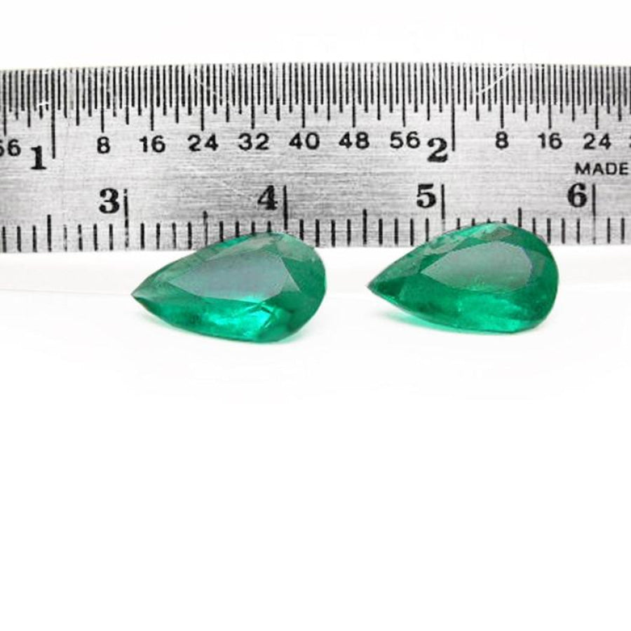 Matched pair of 3.62 carat pear-cut bluish-green Colombian emeralds with a ruler for scale.