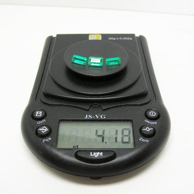 Three emerald-cut natural Colombian emeralds, 4.18 carats, on a black digital jewelry scale.