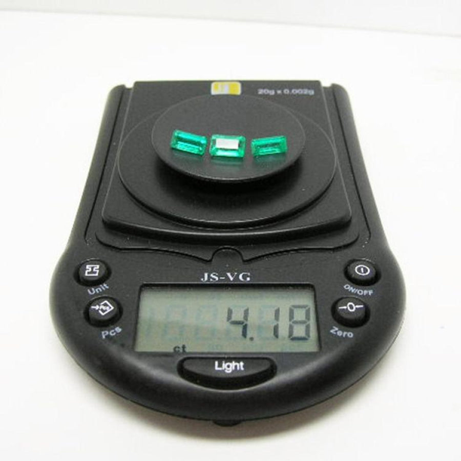 Three emerald-cut natural Colombian emeralds, 4.18 carats, on a black digital jewelry scale.