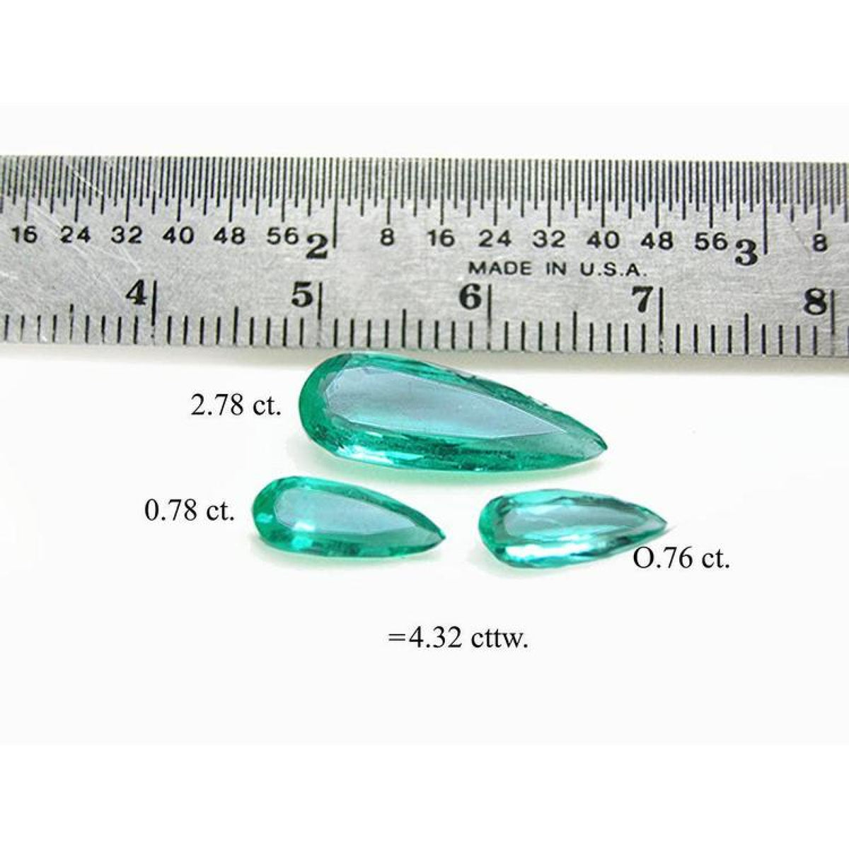 4.32 ct pear-shaped Colombian emeralds in a matching set, shown with a ruler for scale.