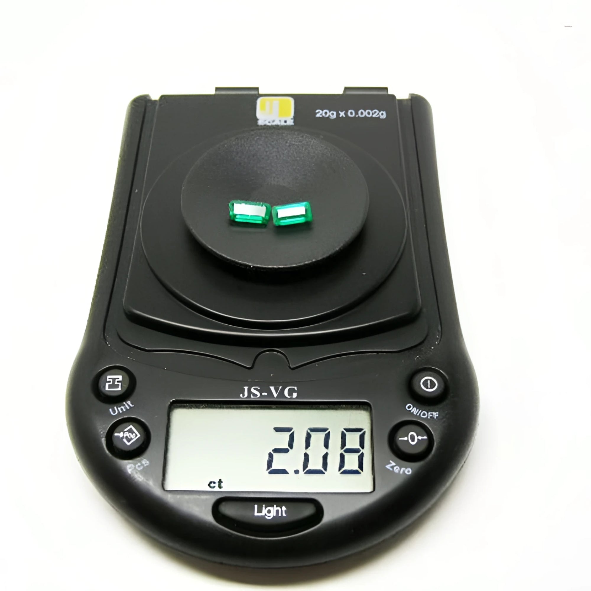 Matched pair of 2.08 ct. natural emerald-cut emeralds on a black digital scale.