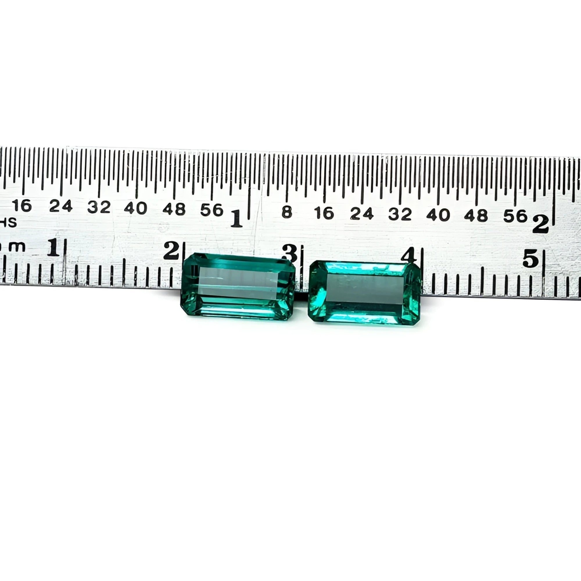 Emerald-cut 3.38 ct. matching pair loose emeralds with vibrant bluish-green color, displayed next to a ruler.