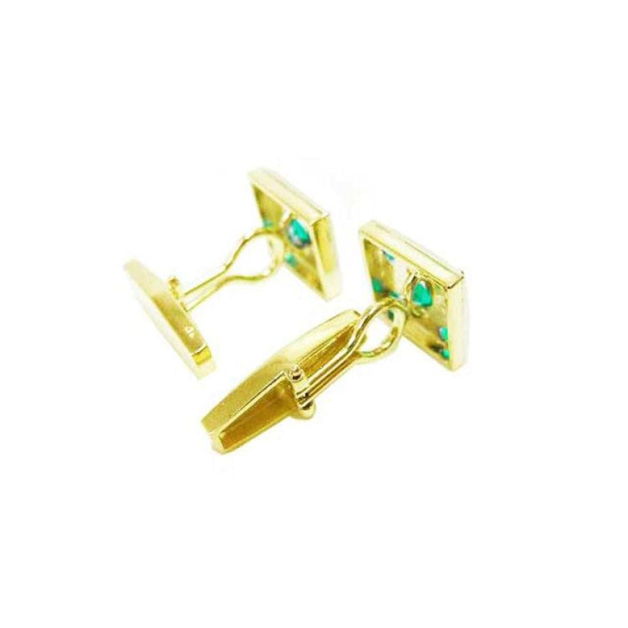Pair of 14K yellow gold cufflinks with square emerald-set faces and a hinged back.