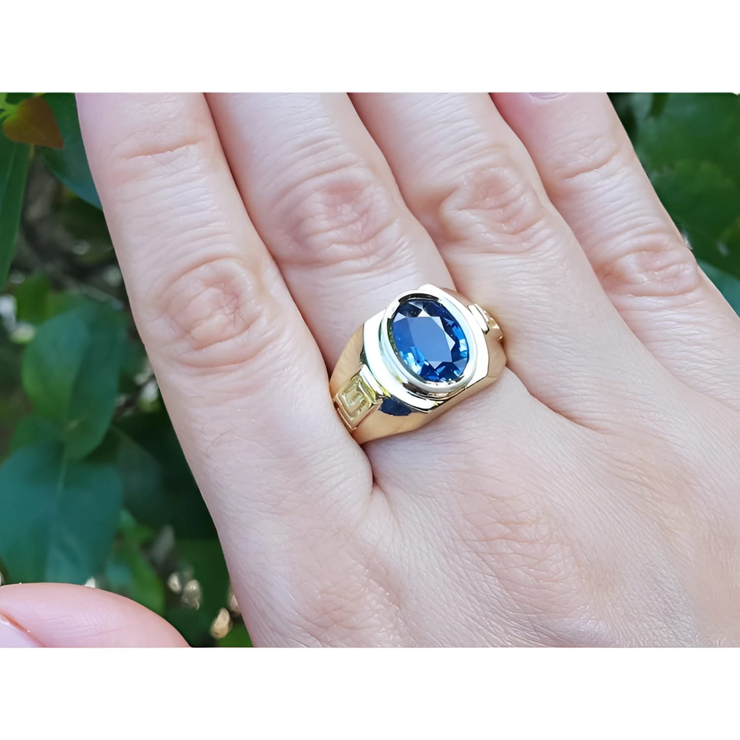 Men's 18K yellow gold ring with oval blue sapphire and Greek key design.