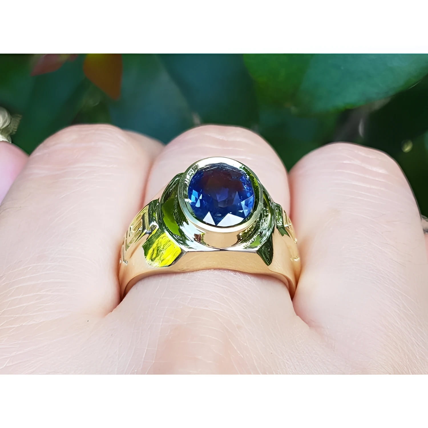 Men's 18K yellow gold ring with a bezel-set oval blue sapphire and Greek key design.