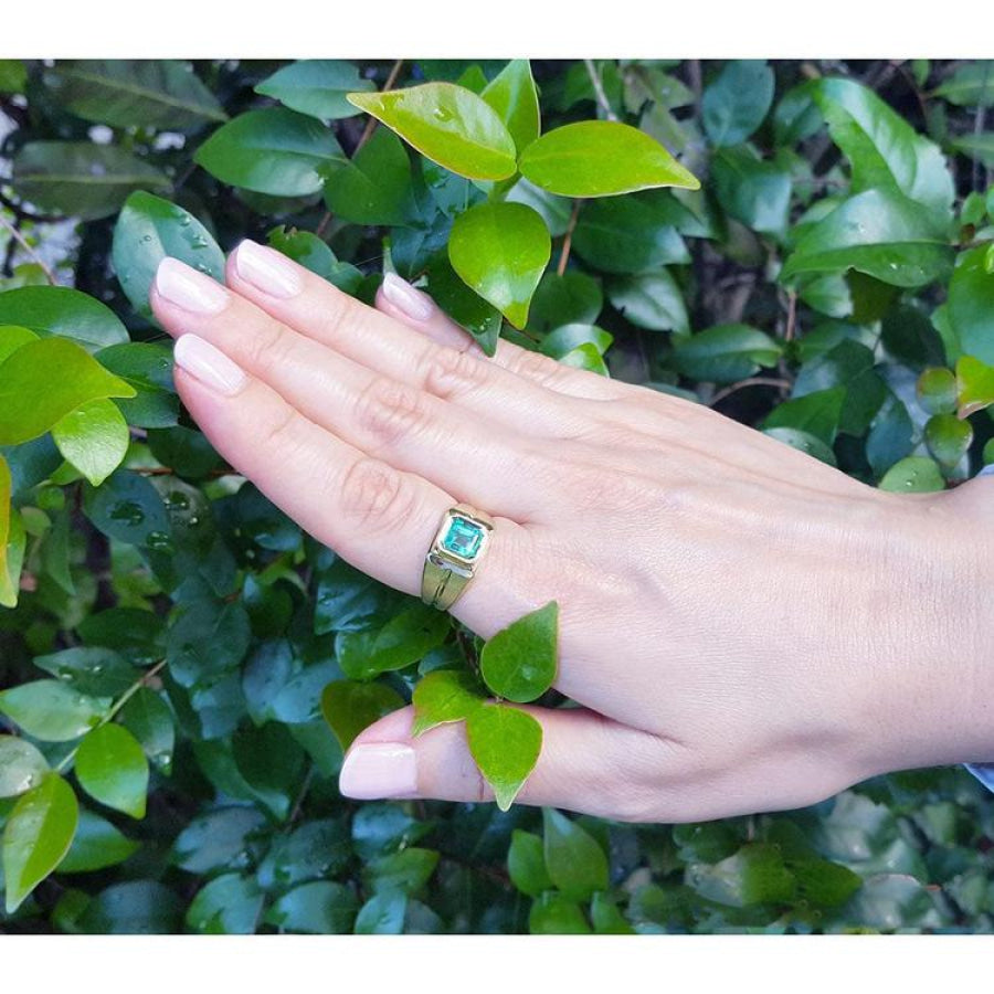 Men's 18K yellow gold pinky ring with a bezel-set, square-cut green emerald on a hand.