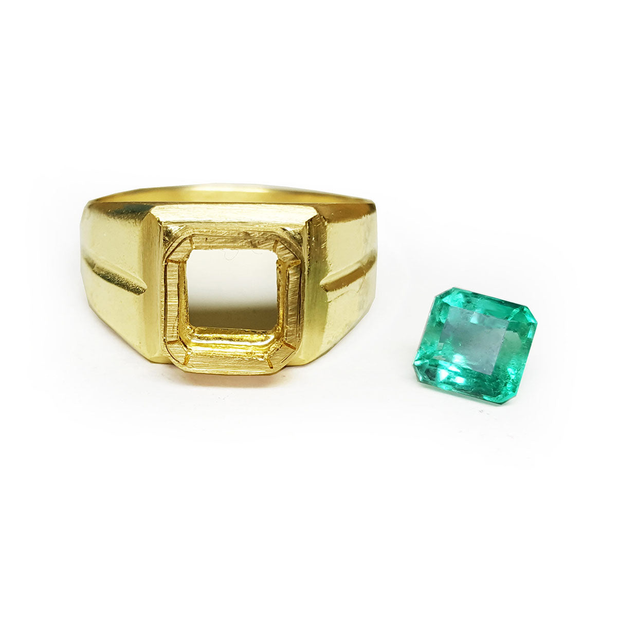A yellow gold mounting ring with a loose colombian emerald aside to be set.