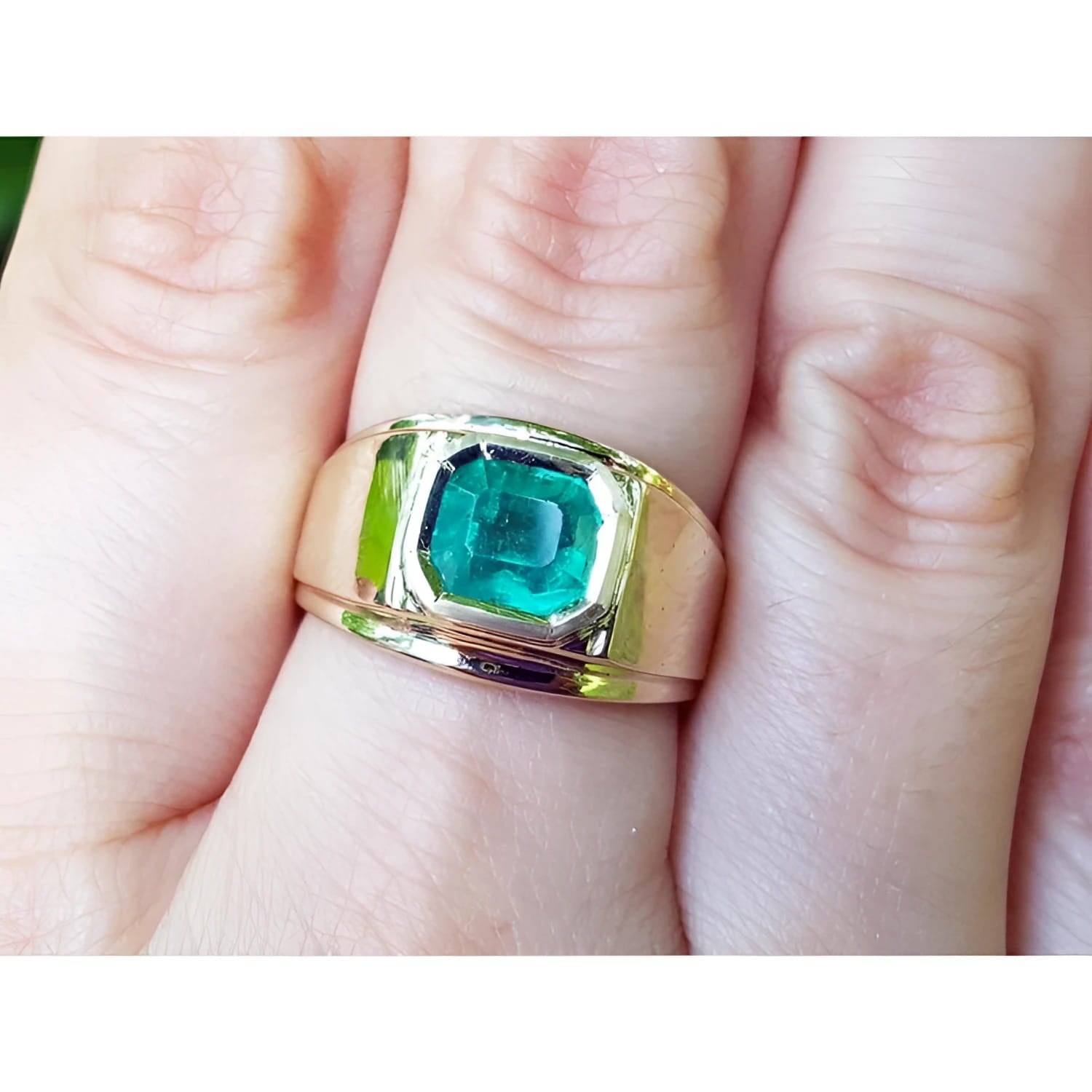 A men’s solitaire ring featuring a square natural Colombian emerald, bezel-set in 14k gold, worn on the hand.