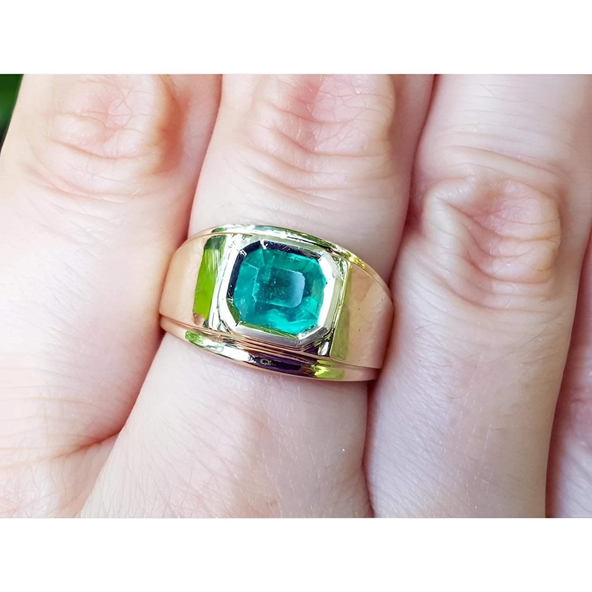 A men’s solitaire ring featuring a square natural Colombian emerald, bezel-set in 14k gold, worn on the hand.