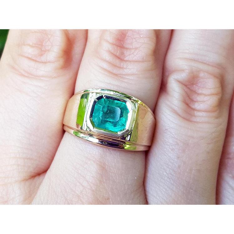 A men’s solitaire ring featuring a square natural Colombian emerald, bezel-set in 14k gold, worn on the hand.