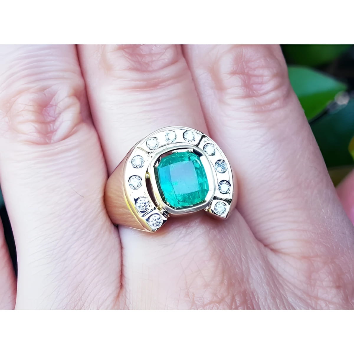 A 14k gold men’s emerald ring featuring a horseshoe design with accent diamonds, worn on the hand.