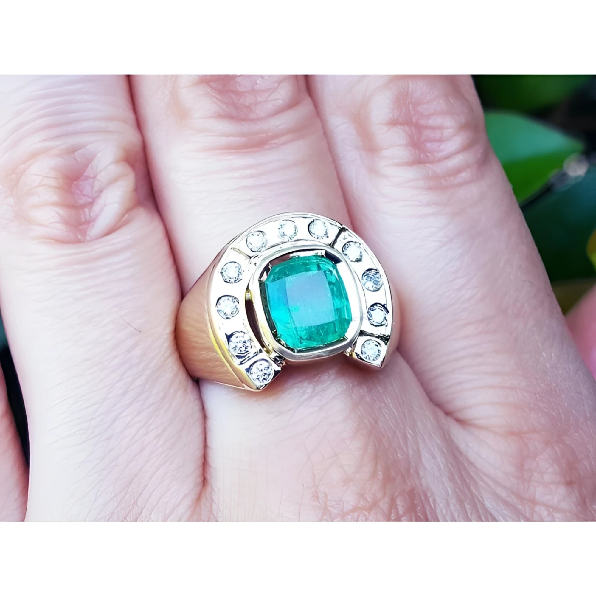A 14k gold men’s emerald ring featuring a horseshoe design with accent diamonds, worn on the hand.