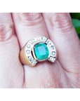 A gold men's emerald ring horseshoe design with accent diamonds on a hand.