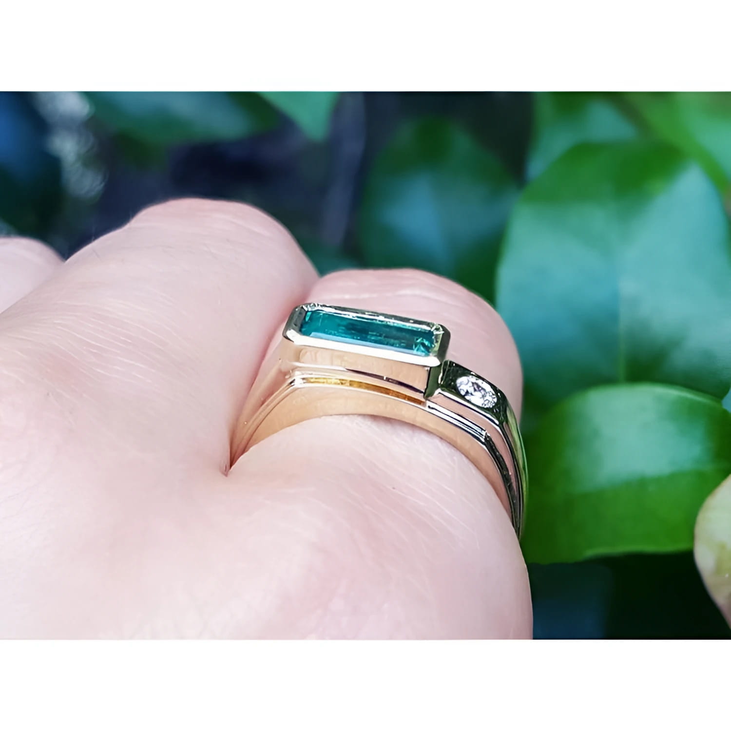 Men's 14K yellow gold ring with a deep green rectangular emerald and a side diamond.