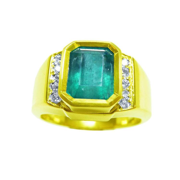 A bezel set natural emerald ring for men with accent diamonds crafted in 18k yellow gold. 