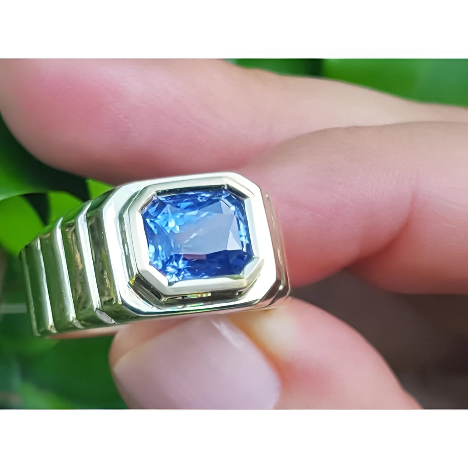 Men's 18k yellow gold ring with a vibrant blue octagonal emerald cut sapphire, bezel set.