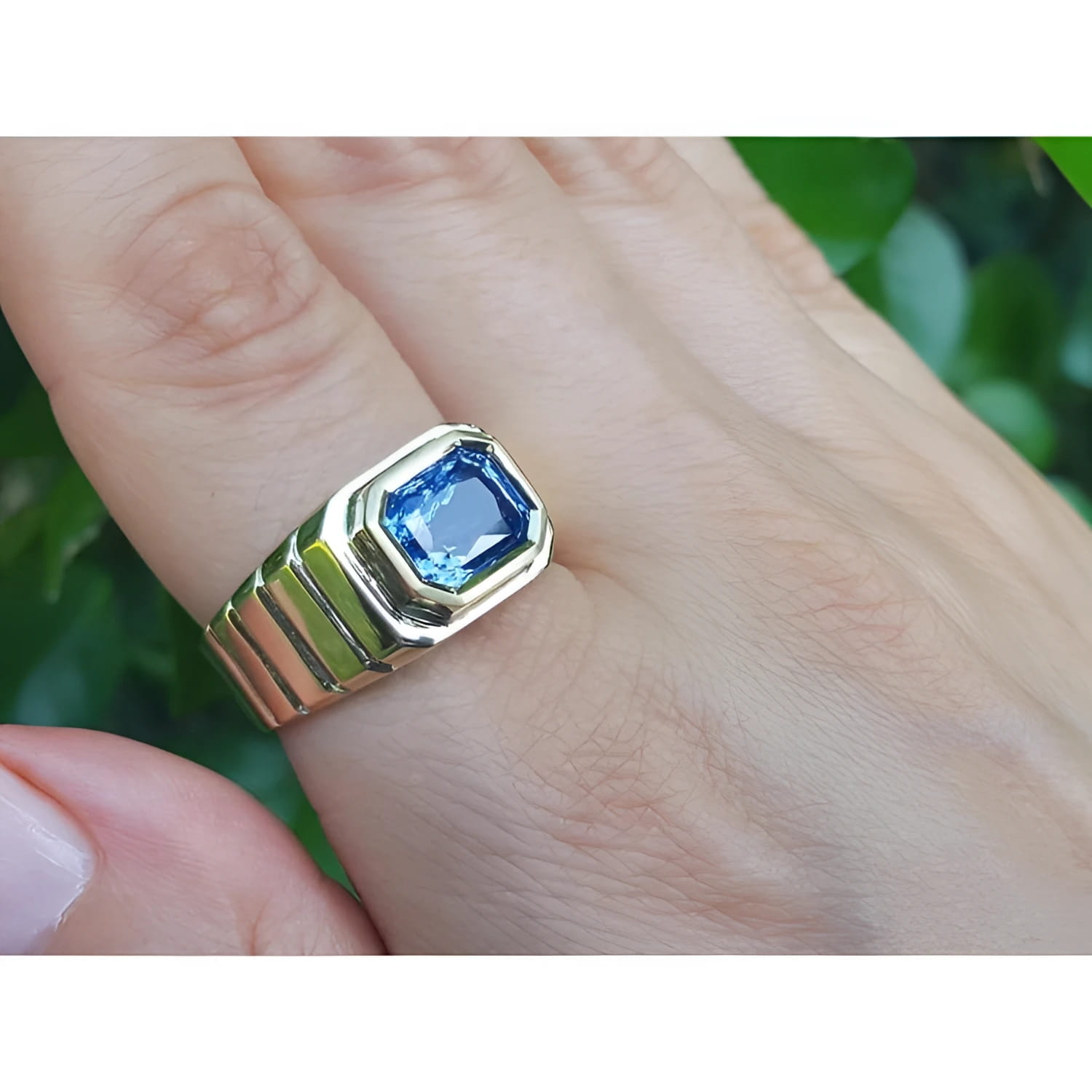 Men's 18k yellow gold ring with a vibrant blue octagonal emerald cut sapphire, bezel set east-west.