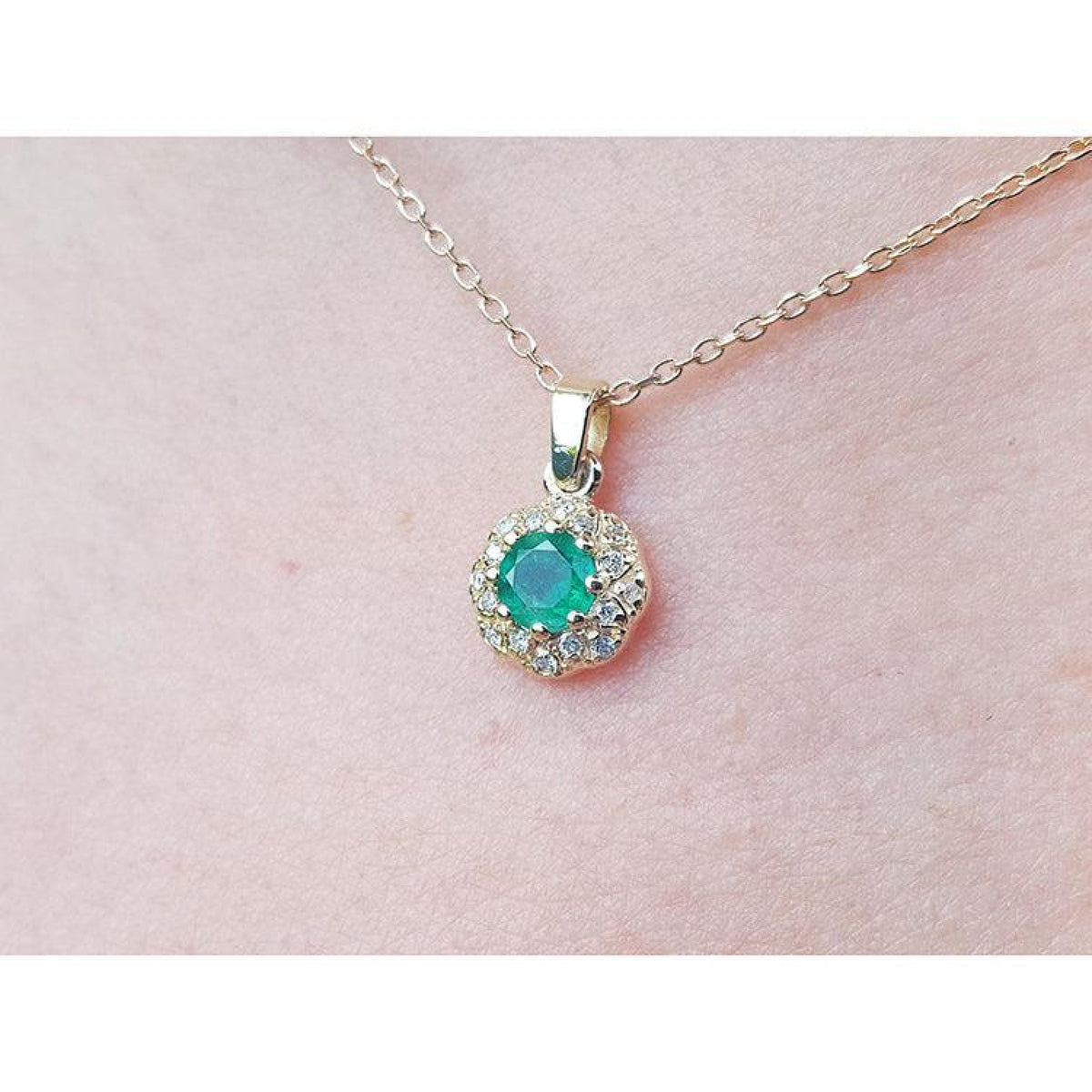 Colombian round cut emerald and diamond pendant on a 14K yellow gold minimalist necklace.