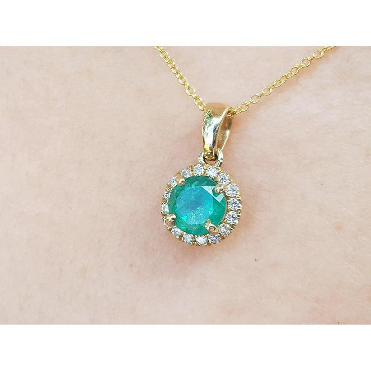 Round cut 0.61 ct. deep green Colombian emerald necklace with halo diamonds in 14k yellow gold.