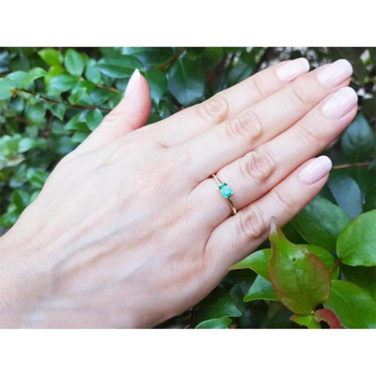 Minimalist 0.35 ct. emerald solitaire ring, east-west set in 14K yellow gold on a hand.