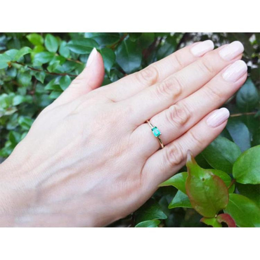Minimalist 0.35 ct. emerald solitaire ring, east-west set in 14K yellow gold on a hand.