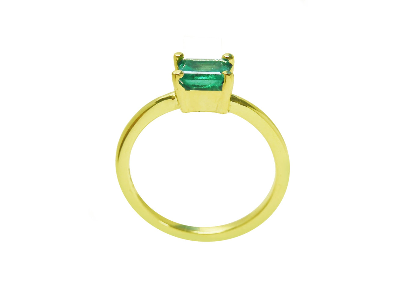 A lateral view of a minimalist emerald solitaire ring representing May&#39;s birthstone jewelry.