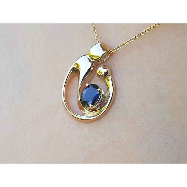 Displaying a gold pendant with a natural blue sapphire on a woman's collar neck