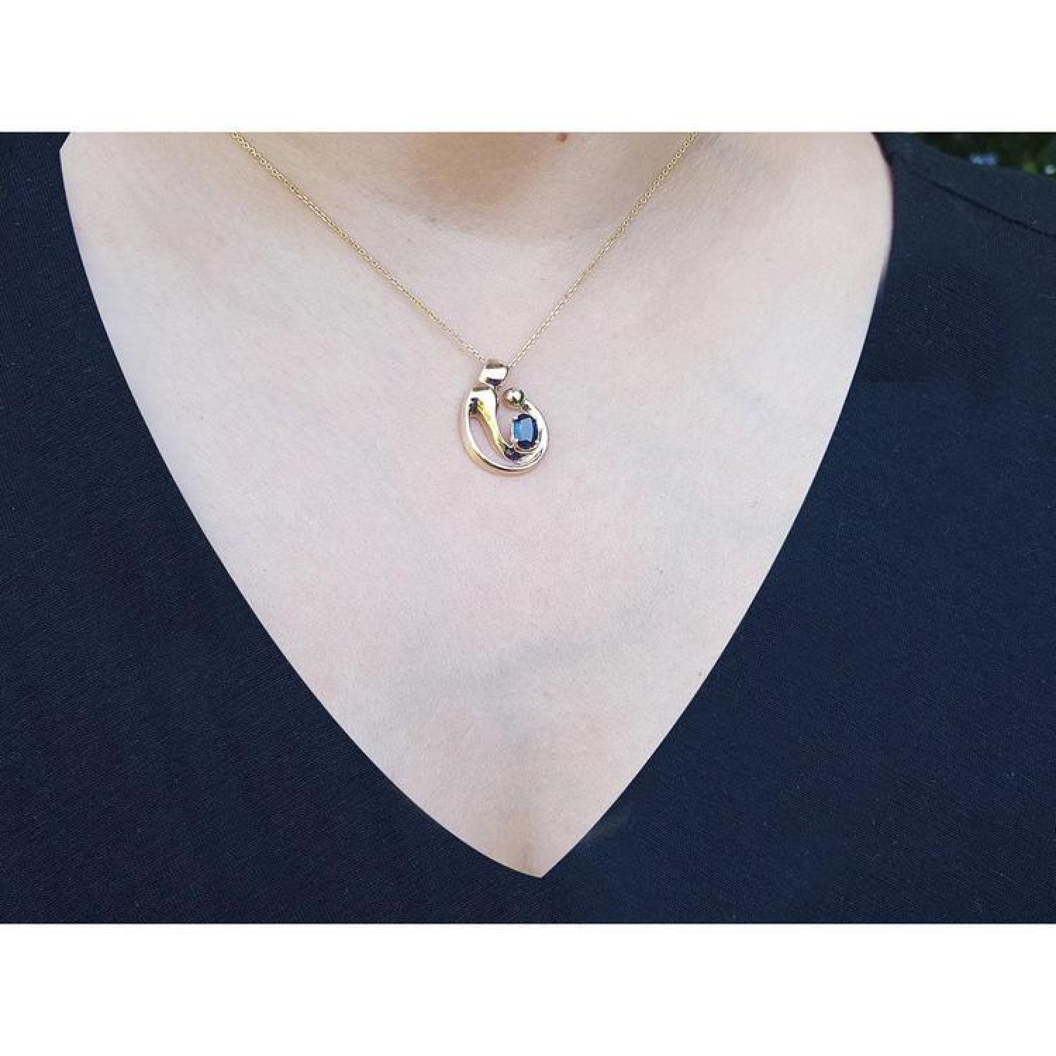 14K yellow gold mother and child sapphire slider pendant necklace on a woman's neck.