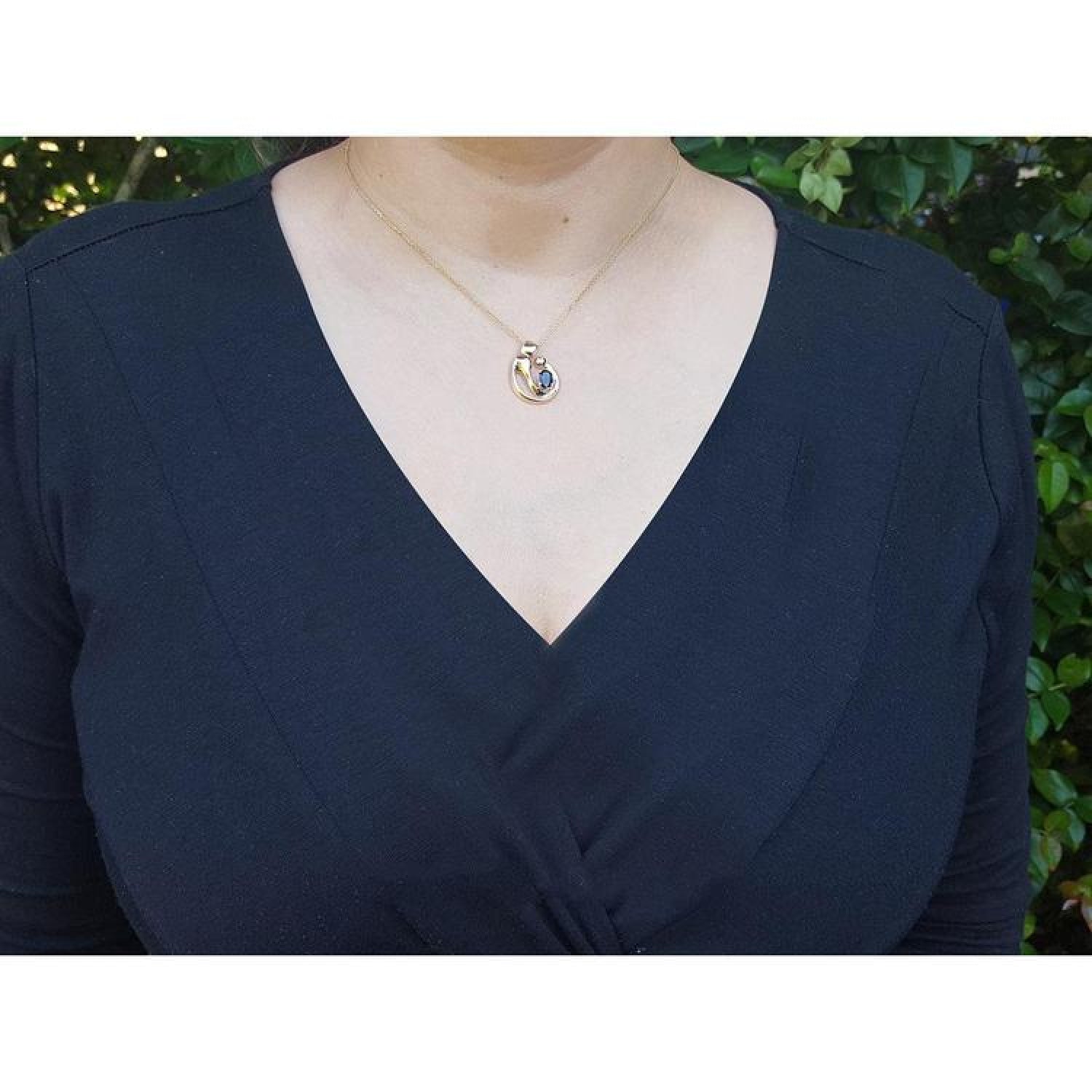 14K yellow gold mother and child sapphire pendant necklace on a woman's chest.