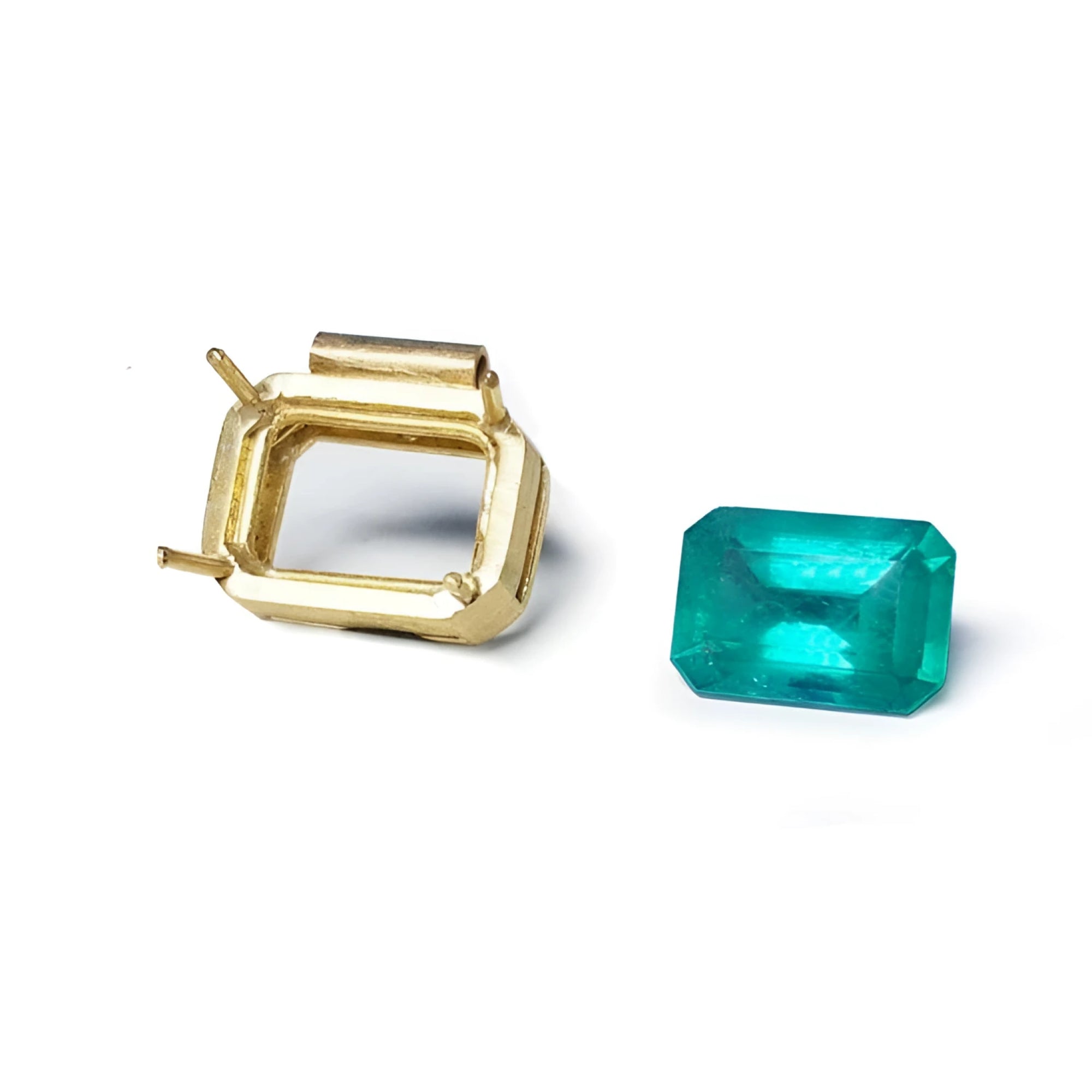 18K yellow gold slider pendant setting next to a vibrant deep green emerald.