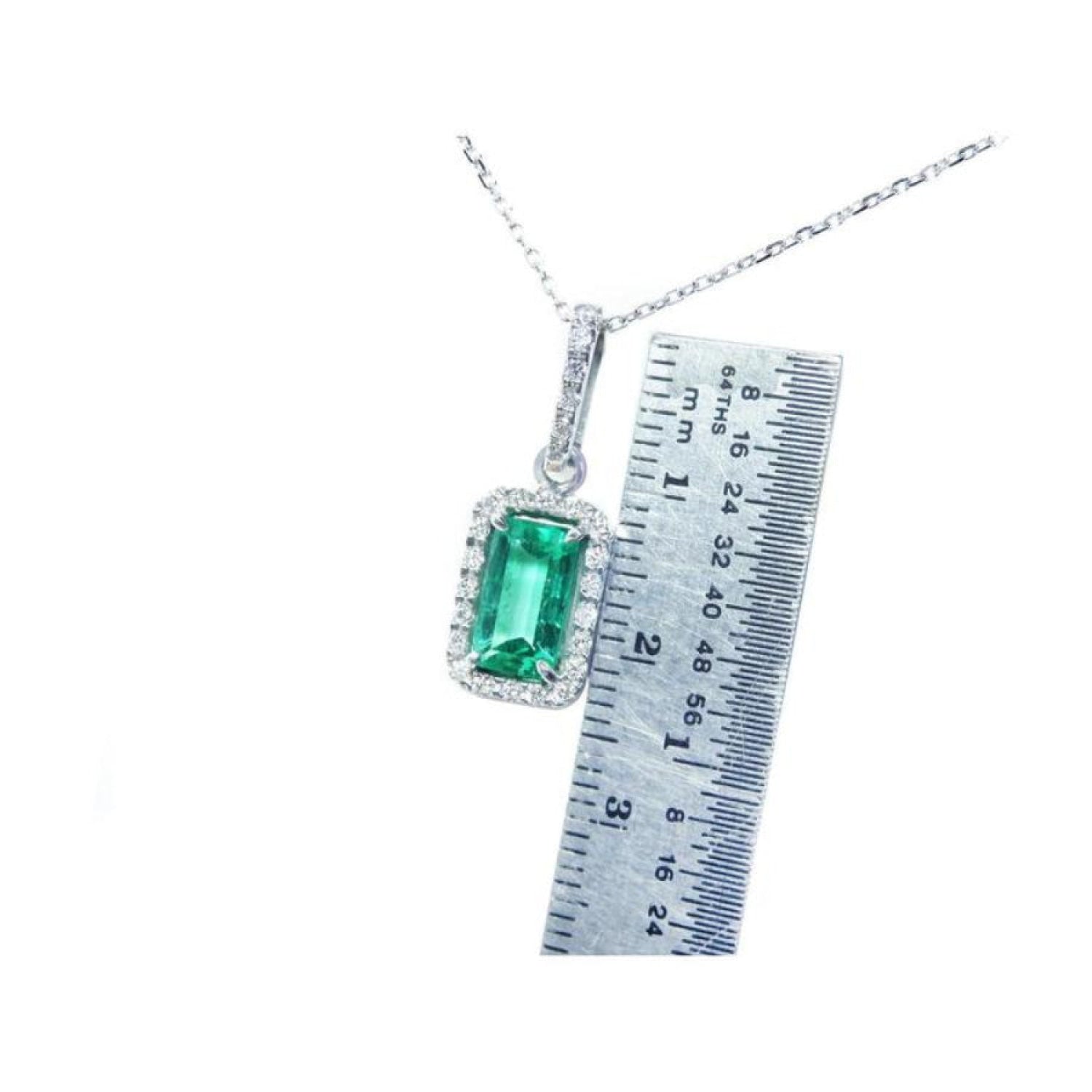 1.70 ct Muzo Colombian emerald pendant with diamond halo in 18K white gold, shown with ruler for scale.