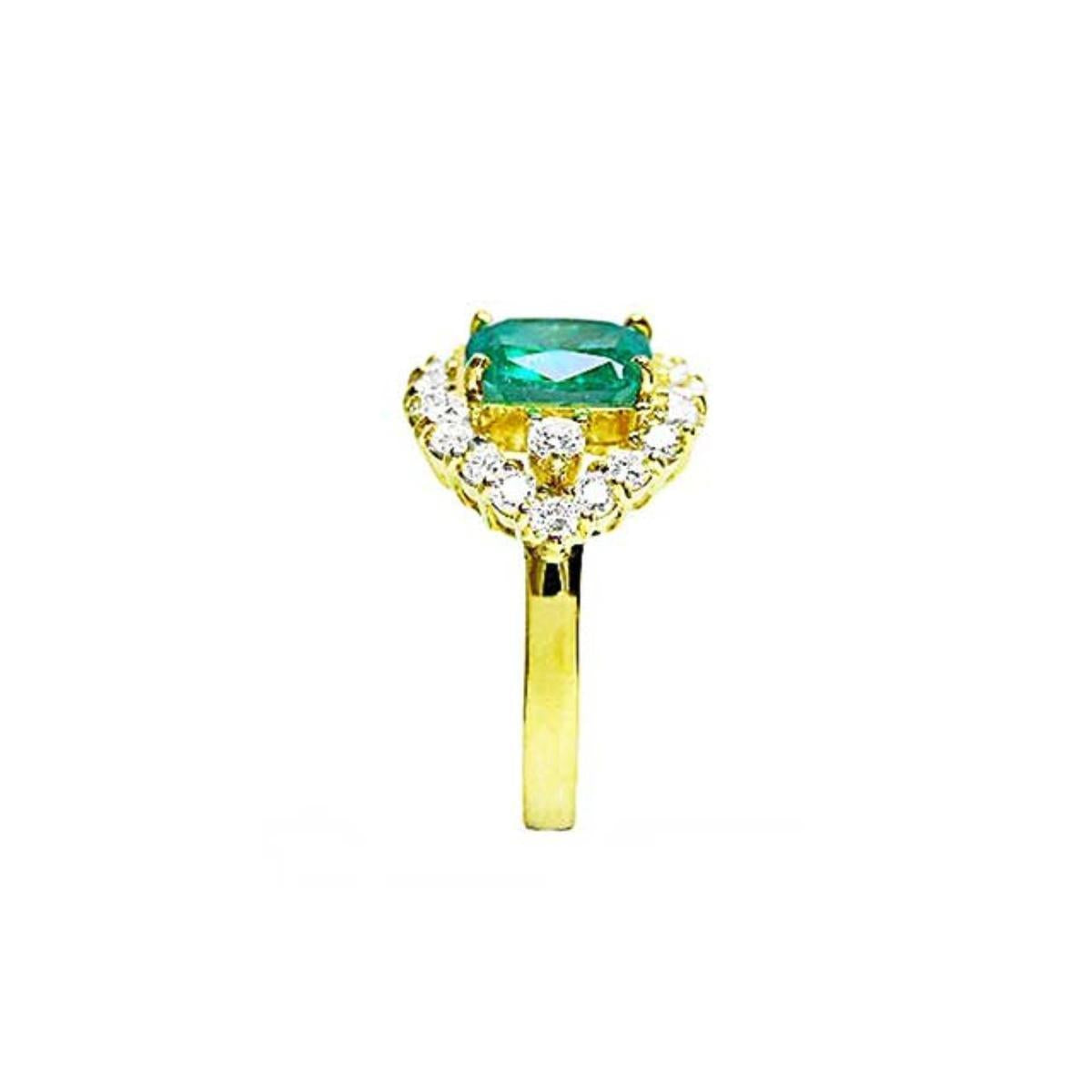 A Muzo colombian emerald ring displaying the top center piece, a halo diamond and the band in yellow gold.