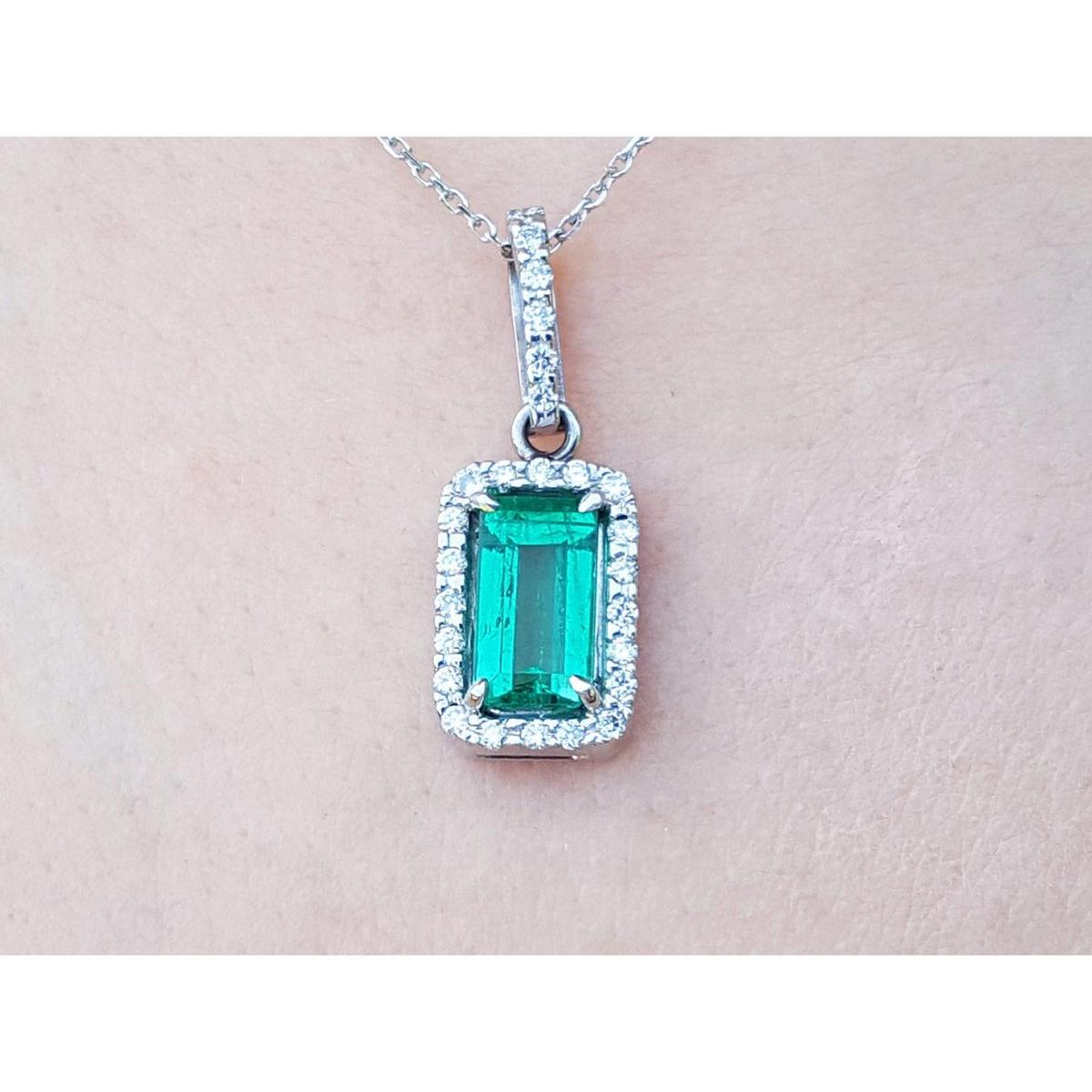 White gold emerald pendant with diamond accents on a light pink skin background.