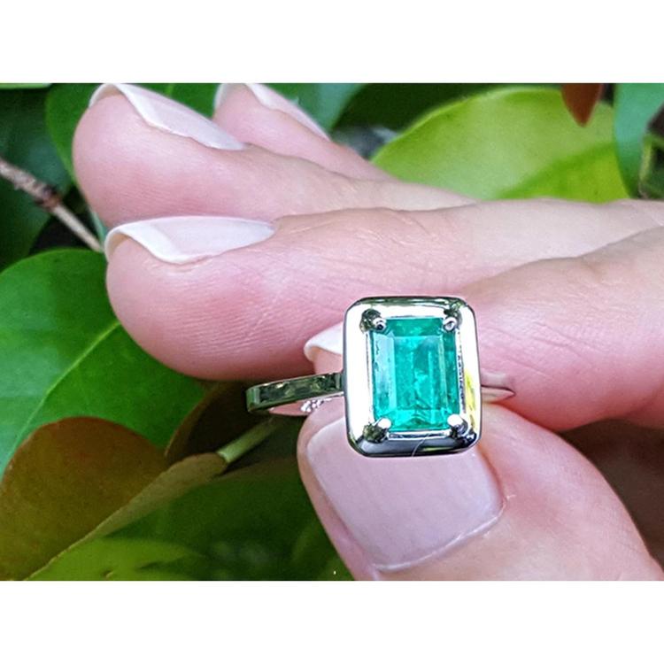 1.50 carat Muzo Colombian emerald solitaire ring in 18K white gold, rectangular cut, prong set.