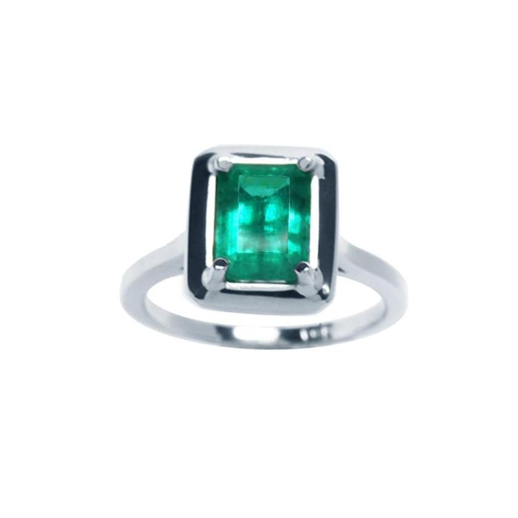 This Muzo Colombian emerald solitaire ring features a rectangular emerald-cut stone set in prongs of 18k white gold.