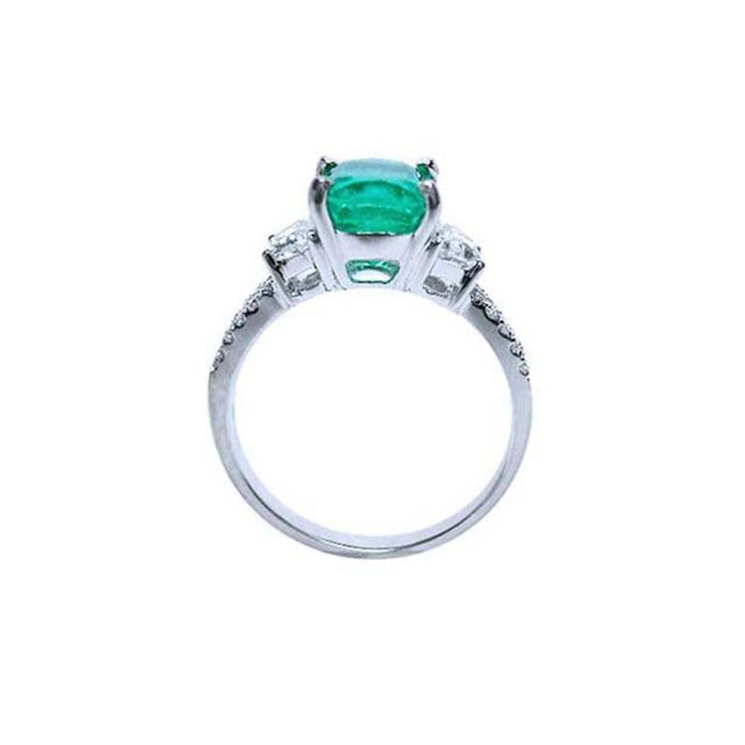 18K white gold ring with a cushion cut emerald and trapezoid side diamonds.