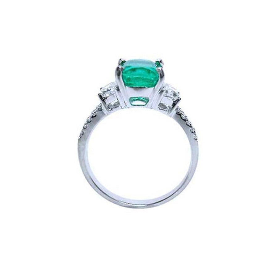 18K white gold ring with a cushion cut emerald and trapezoid side diamonds.