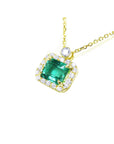 1.31 ct emerald-cut Muzo Colombian emerald necklace with diamond halo in 14K yellow gold.