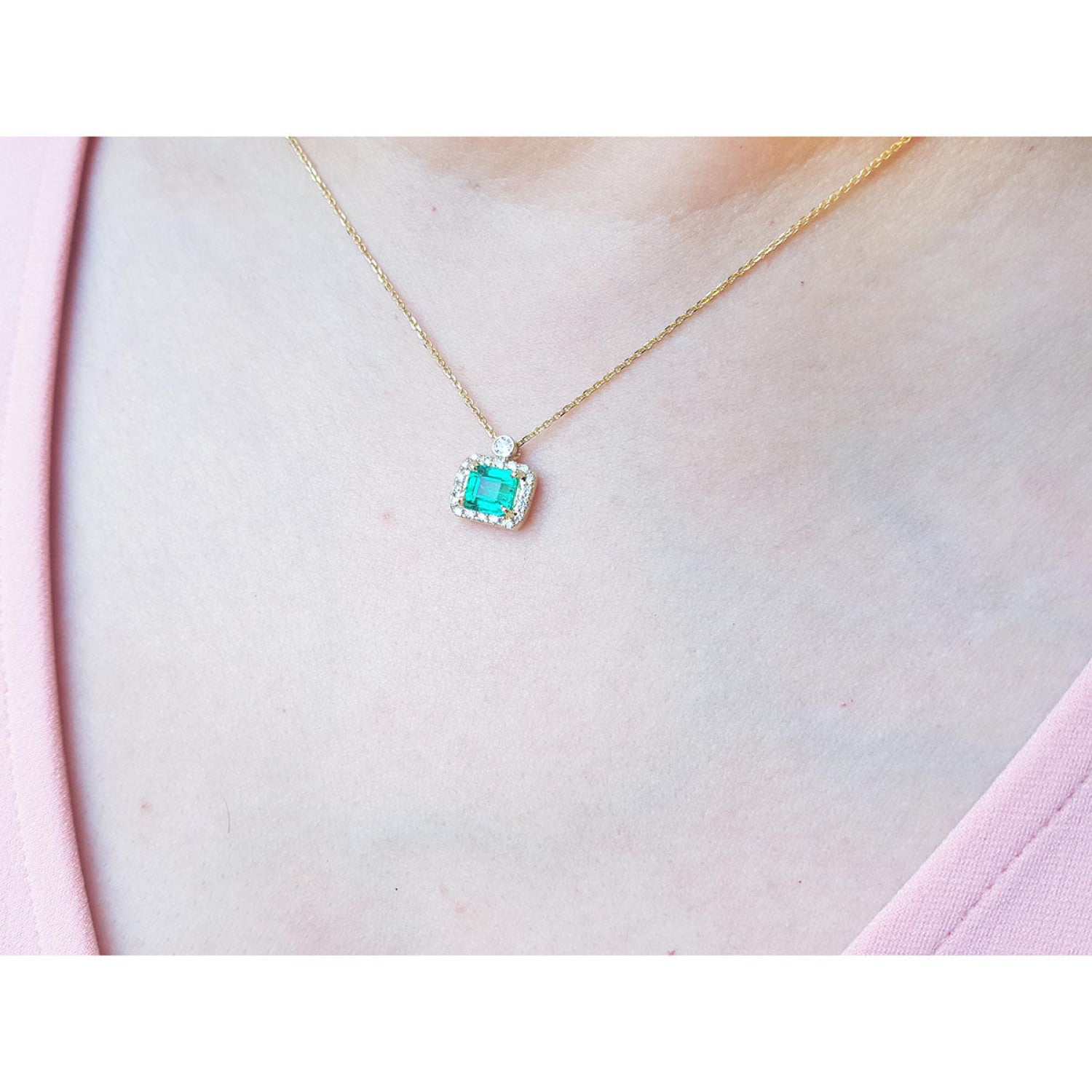 1.31 ct emerald-cut Muzo Colombian emerald necklace with diamonds in 14K yellow gold on a model.