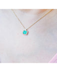 1.31 ct emerald-cut Muzo Colombian emerald necklace with diamonds in 14K yellow gold on a model.