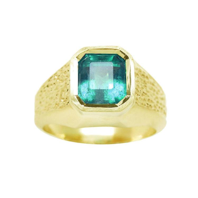A men's solitaire ring yellow gold with a bezel set natural Muzo mine colombian emerald top and sides perspective view.