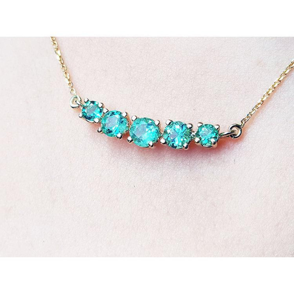 14K gold necklace with five round, medium light green Colombian emeralds, graduated in size.