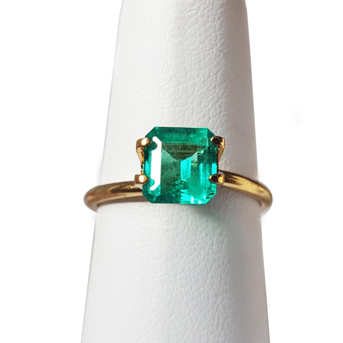 Emerald-cut Muzo mine loose Colombian emerald in a gold mounting display